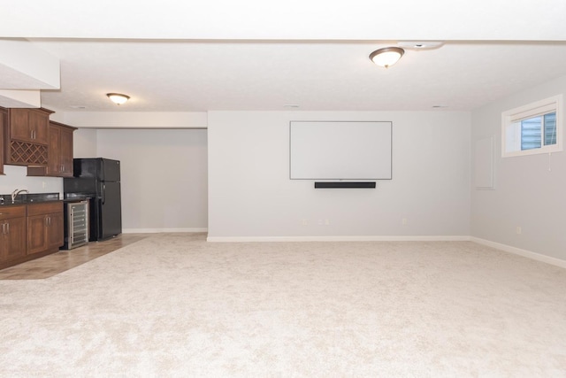 living area featuring wine cooler, baseboards, light carpet, and wet bar