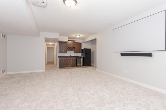 unfurnished living room featuring wine cooler, visible vents, and baseboards