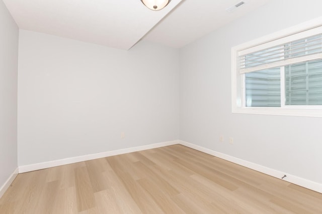 spare room with light wood-style floors, visible vents, and baseboards