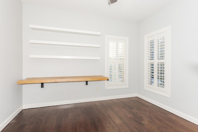 spare room featuring baseboards and dark wood finished floors