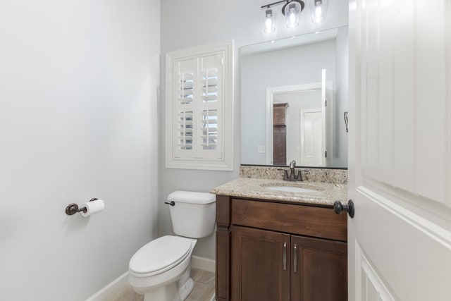 half bathroom with vanity, toilet, and baseboards