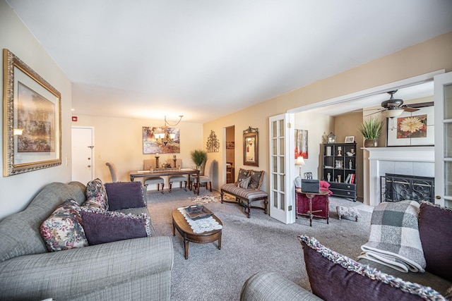 carpeted living room featuring french doors, a fireplace, and ceiling fan with notable chandelier