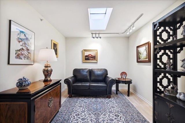 sitting room with a skylight, light hardwood / wood-style floors, and rail lighting