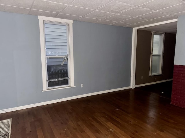 empty room featuring a drop ceiling and dark wood-type flooring