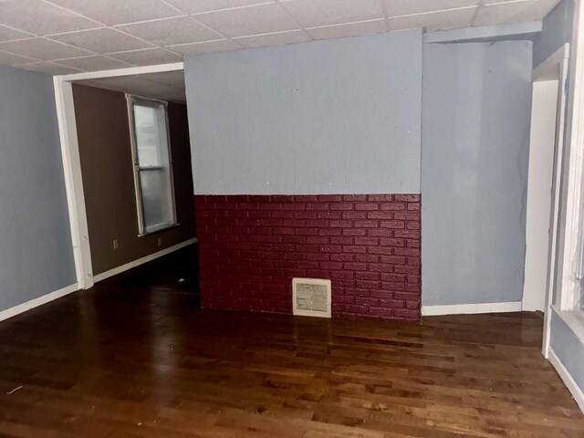 empty room featuring dark wood-type flooring and a paneled ceiling