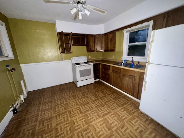 kitchen featuring sink, dark parquet flooring, ceiling fan, dark brown cabinets, and white appliances