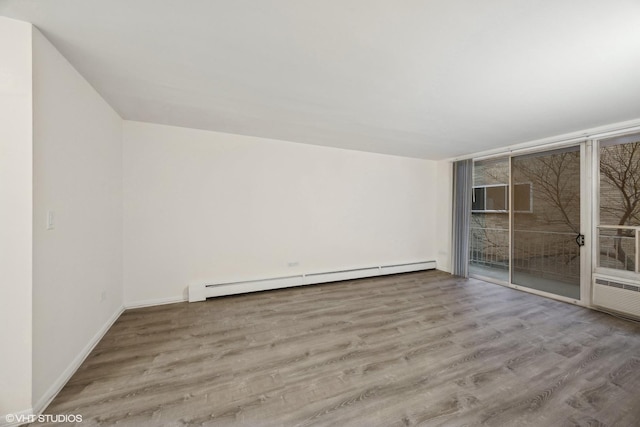 unfurnished room with baseboard heating and light hardwood / wood-style flooring