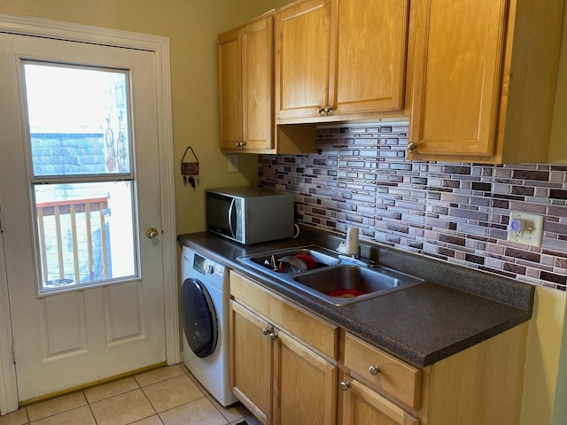 kitchen featuring light tile patterned flooring, washer / clothes dryer, sink, and decorative backsplash