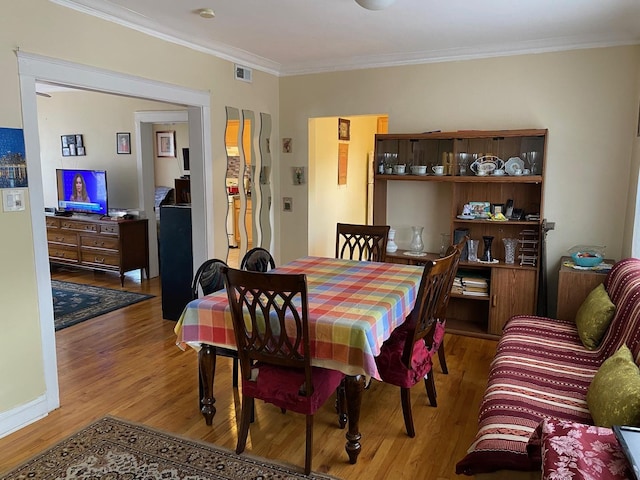 dining space featuring crown molding and light wood-type flooring