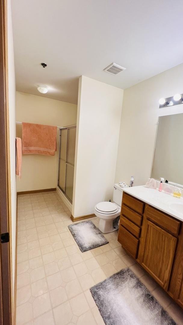 bathroom featuring vanity, toilet, and a shower with shower door