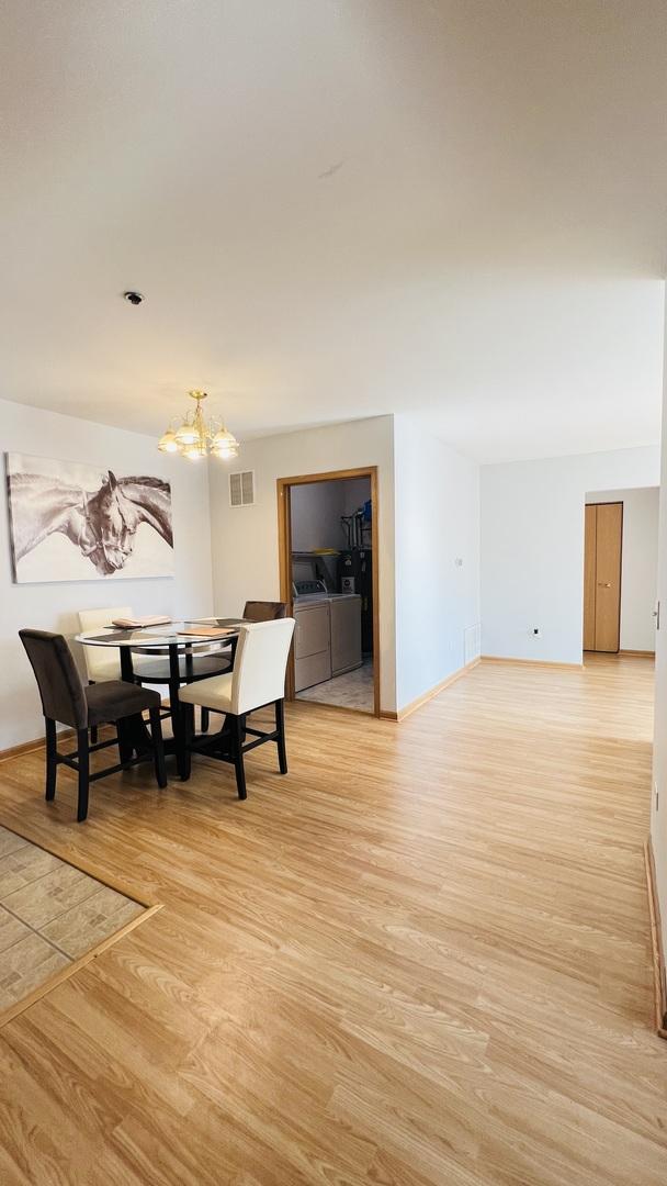 dining area featuring light hardwood / wood-style floors, washing machine and dryer, and a notable chandelier