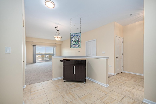 kitchen with dark brown cabinetry, hanging light fixtures, and light tile patterned floors