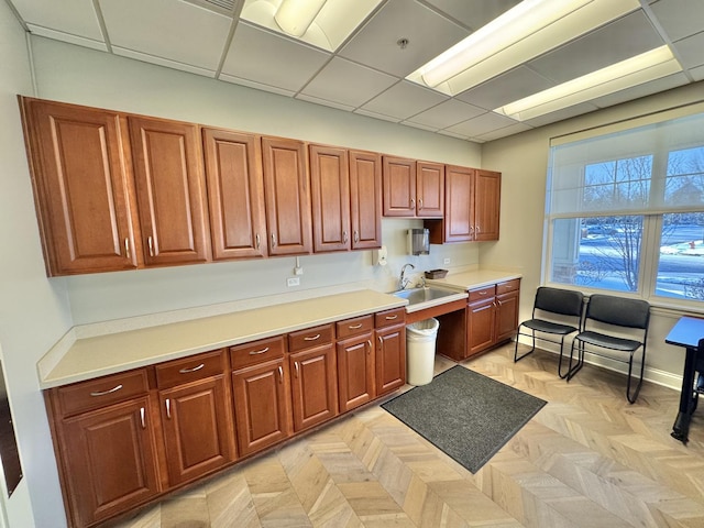 kitchen featuring light parquet floors, sink, and a drop ceiling