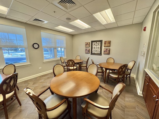 dining area featuring a drop ceiling and light parquet floors