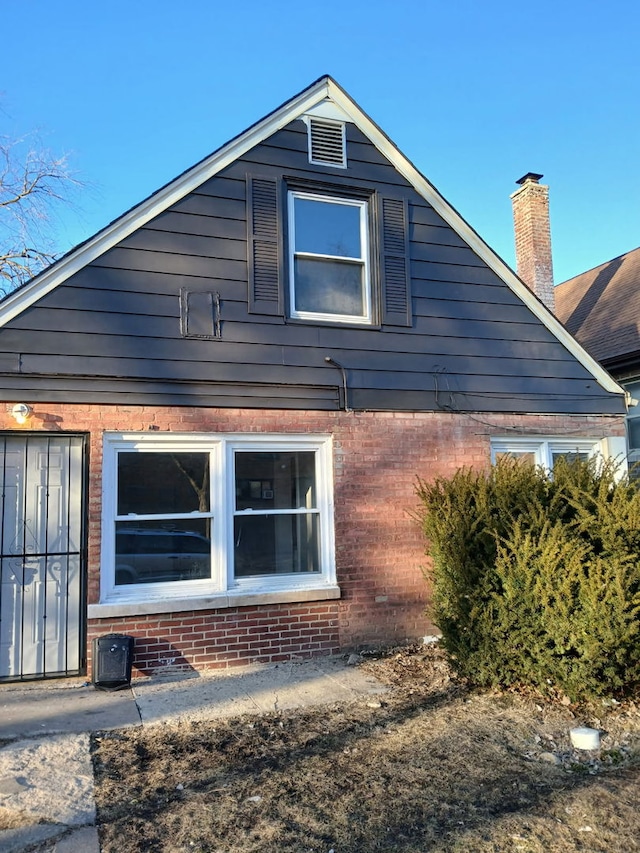 view of side of property with brick siding and a chimney