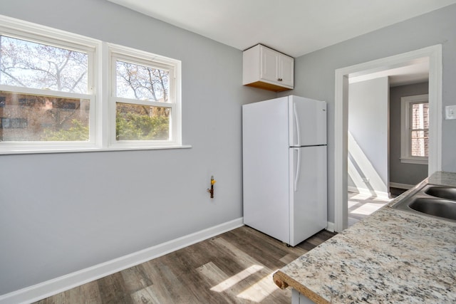 kitchen featuring sink, dark wood-type flooring, white refrigerator, light stone countertops, and white cabinets