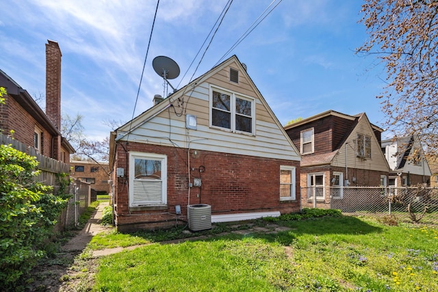 back of property featuring central AC, fence, a lawn, and brick siding