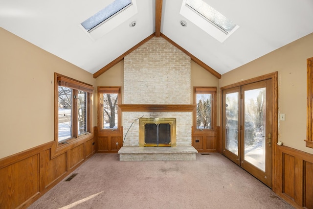 unfurnished living room featuring light carpet, a fireplace, and vaulted ceiling with skylight