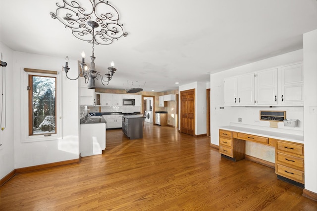 kitchen featuring white cabinetry, dark hardwood / wood-style flooring, built in desk, and an inviting chandelier