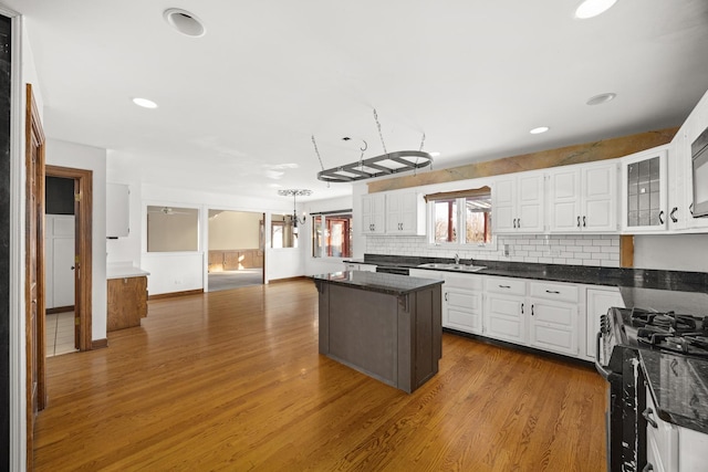 kitchen with gas range, dark wood-type flooring, a kitchen island, and white cabinets