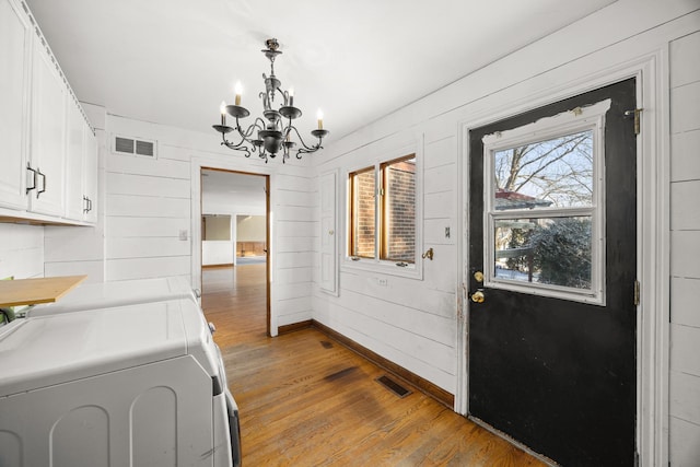 washroom featuring hardwood / wood-style flooring, cabinets, an inviting chandelier, and washing machine and dryer