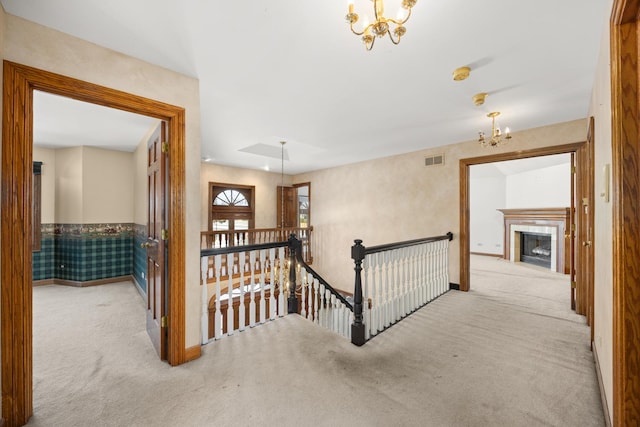 hall featuring an inviting chandelier and light carpet