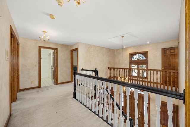 hall with an inviting chandelier and light carpet