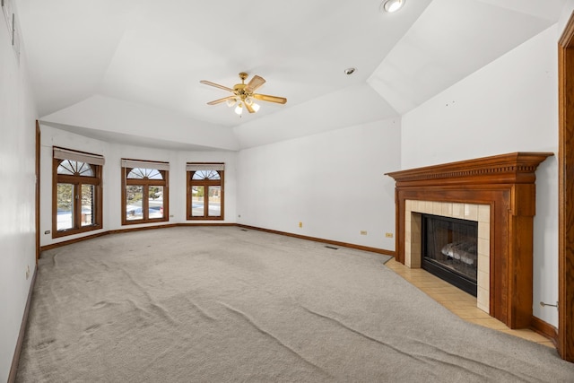 unfurnished living room featuring a tile fireplace, vaulted ceiling, light carpet, and ceiling fan