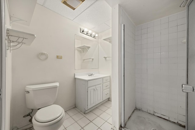 bathroom with vanity, tiled shower, tile patterned floors, and toilet