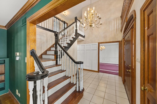 tiled foyer featuring a notable chandelier, ornamental molding, and a high ceiling