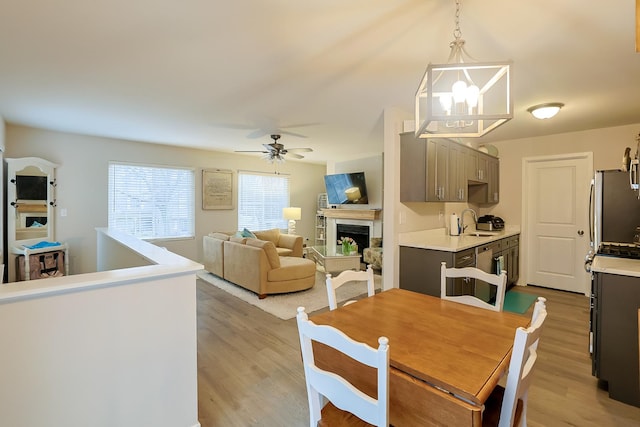 dining area with sink, ceiling fan with notable chandelier, and light hardwood / wood-style floors