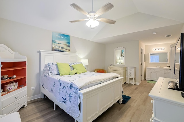 bedroom with vaulted ceiling, connected bathroom, ceiling fan, and light hardwood / wood-style flooring