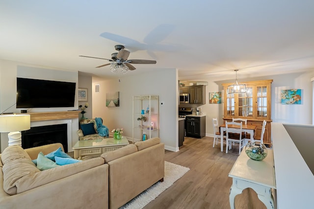 living room with ceiling fan with notable chandelier and light hardwood / wood-style flooring