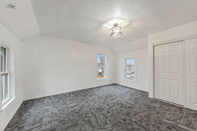 480 E Birch St, Kankakee, IL 60901 - unfurnished bedroom featuring vaulted ceiling, dark carpet, a closet, and a textured ceiling