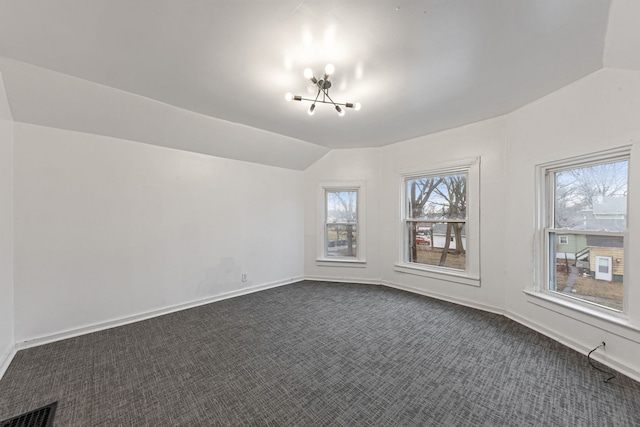 additional living space with dark carpet, vaulted ceiling, and a chandelier