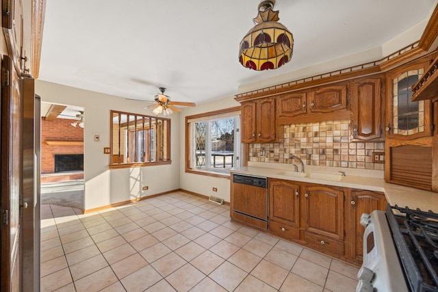 kitchen featuring a fireplace, stainless steel gas stove, tasteful backsplash, sink, and paneled dishwasher