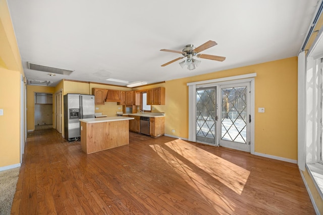 kitchen with dark hardwood / wood-style flooring, a kitchen island, ceiling fan, and appliances with stainless steel finishes