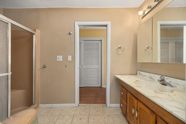 bathroom with vanity, a shower with door, tile patterned floors, and toilet