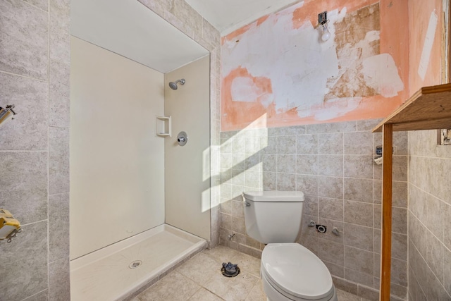 bathroom with tile patterned floors, toilet, tile walls, and a shower