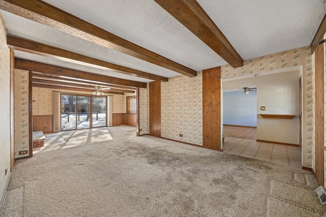 unfurnished living room with ceiling fan, beam ceiling, light colored carpet, and a textured ceiling