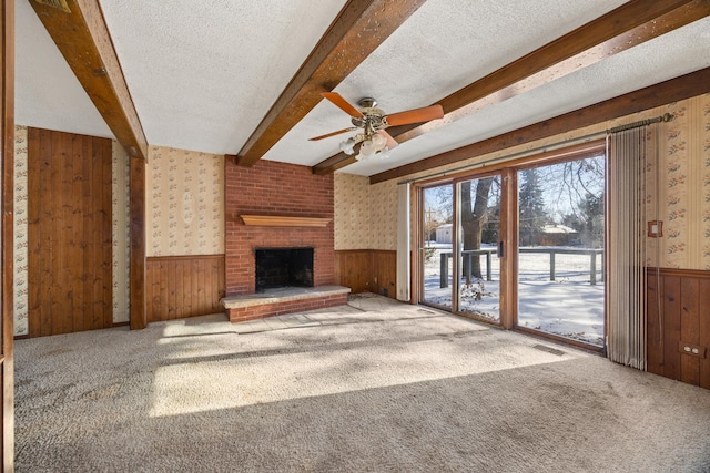 unfurnished living room featuring beamed ceiling, carpet flooring, and a textured ceiling