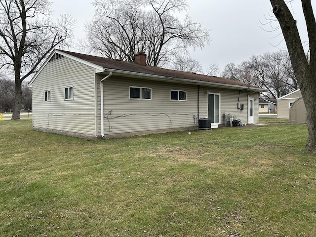 rear view of property featuring central AC unit and a lawn