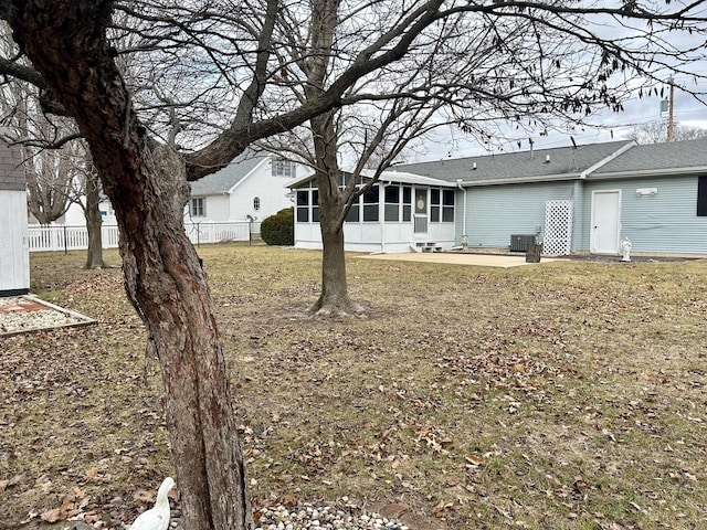 rear view of property featuring central AC unit, a lawn, a sunroom, and a patio