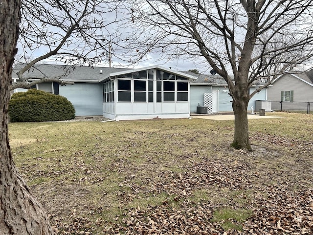 back of house featuring a sunroom, central AC, and a lawn