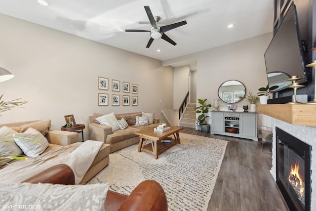 living room with dark hardwood / wood-style flooring, a tile fireplace, and ceiling fan