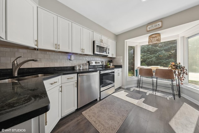 kitchen with sink, dark hardwood / wood-style floors, stainless steel appliances, decorative backsplash, and white cabinets