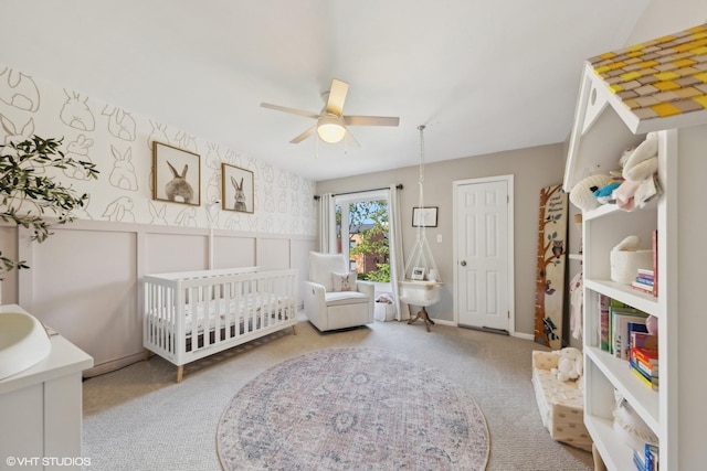 bedroom featuring a crib, light colored carpet, and ceiling fan