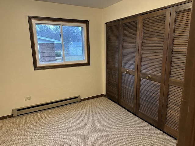 unfurnished bedroom featuring light carpet, a closet, and baseboard heating