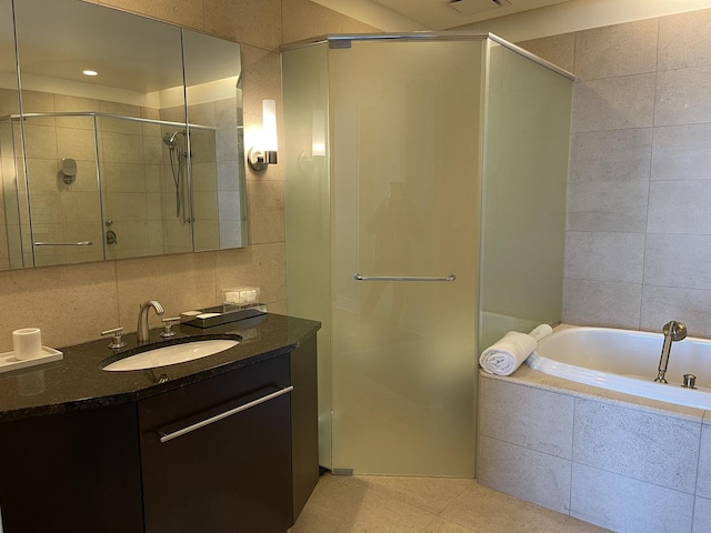 bathroom with tile patterned flooring, plus walk in shower, tile walls, and vanity