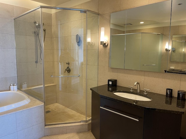 bathroom with independent shower and bath, vanity, tasteful backsplash, and tile walls